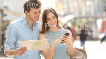 Couple of tourists consulting a city guide and smartphone gps in the street searching locations